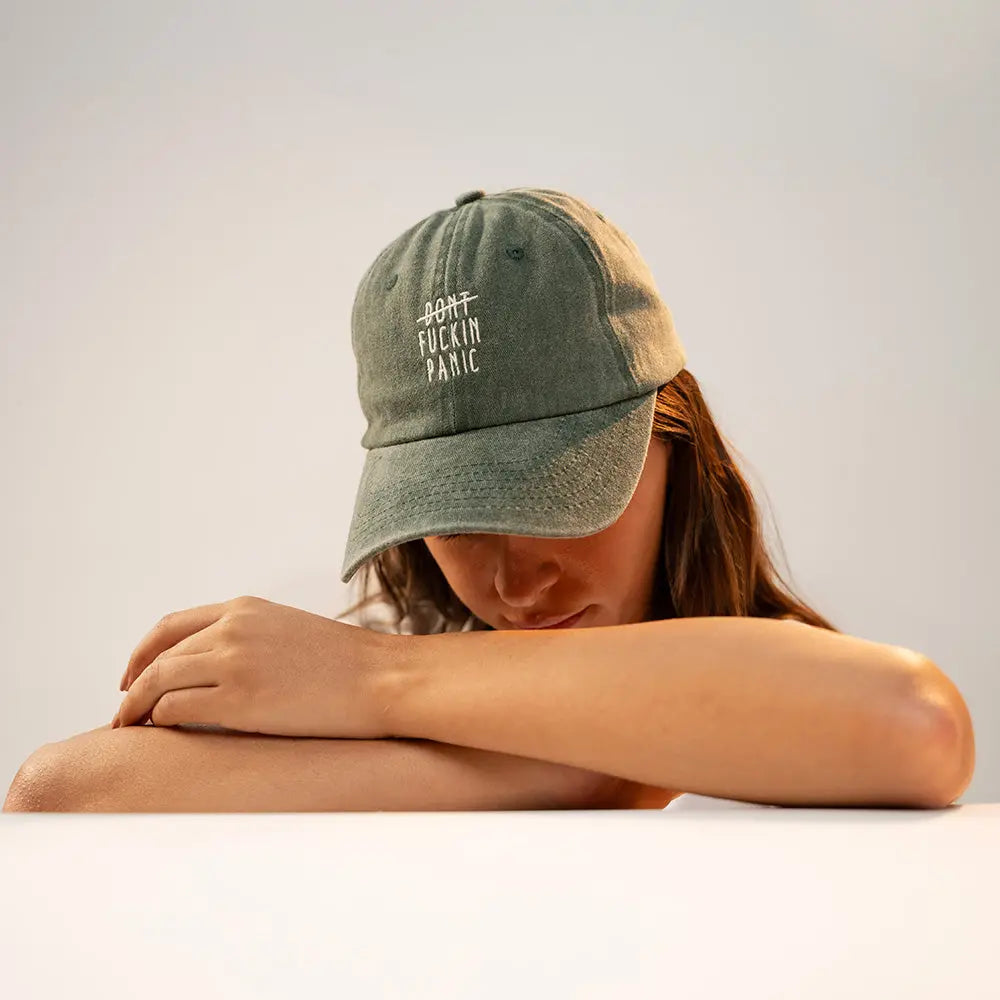 Person wearing a green Panic Zones Don't F**** Panic Cap — official Panic Zones merch