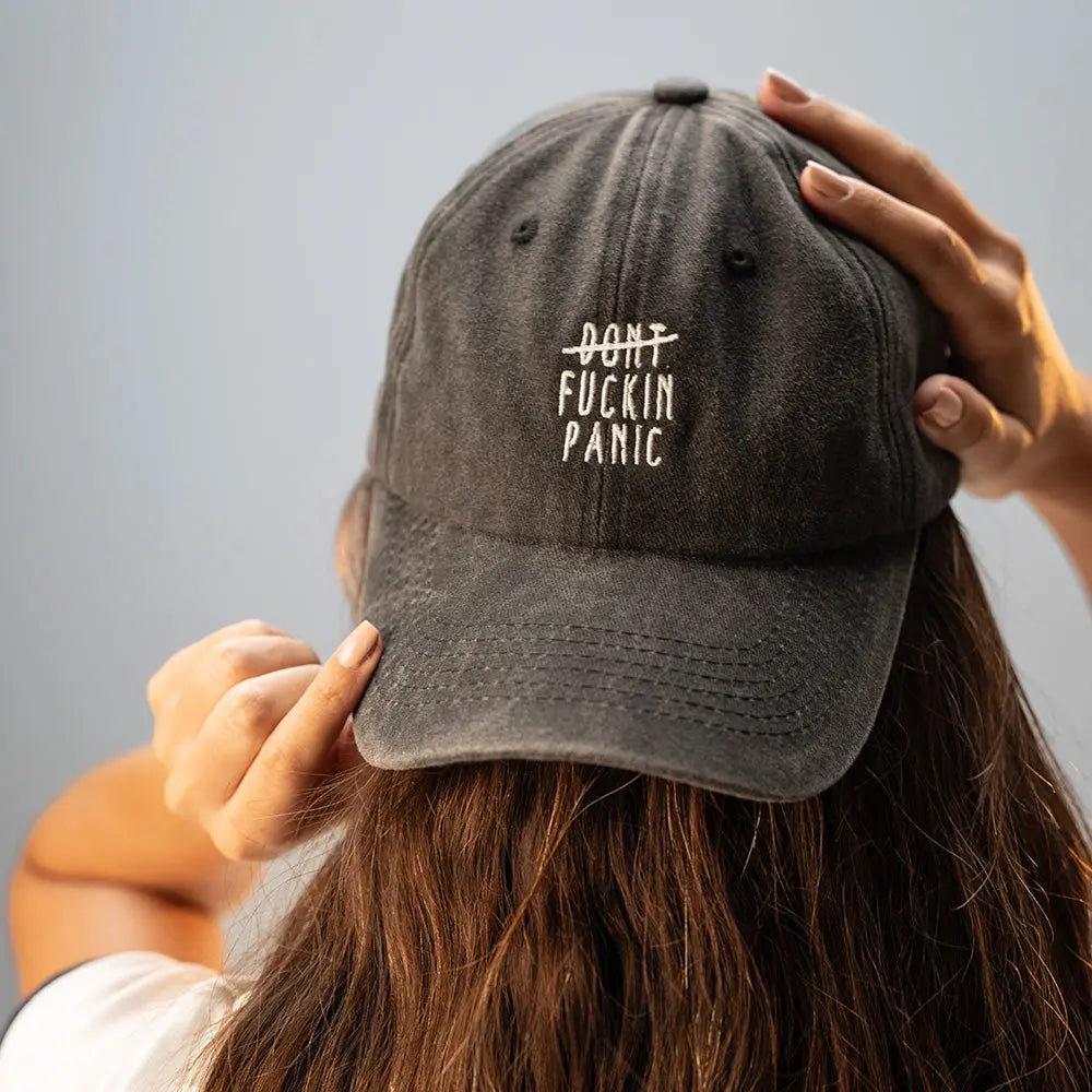 Person wearing a black Panic Zones Don't F**** Panic Cap — official Panic Zones merch