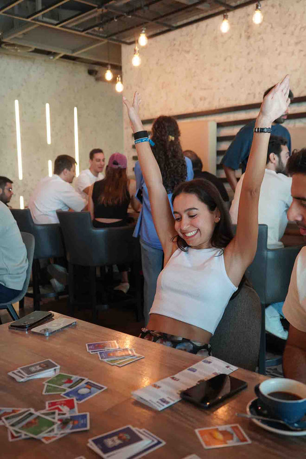 Woman celebrating with hands in the air and panic zones cards on the table
